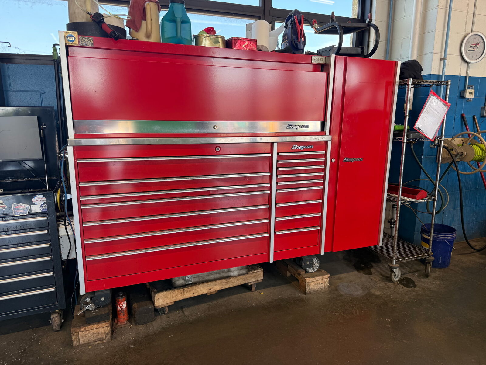 A technician's personal tool storage in a working service bay: roll cab, hutch, and side locker.